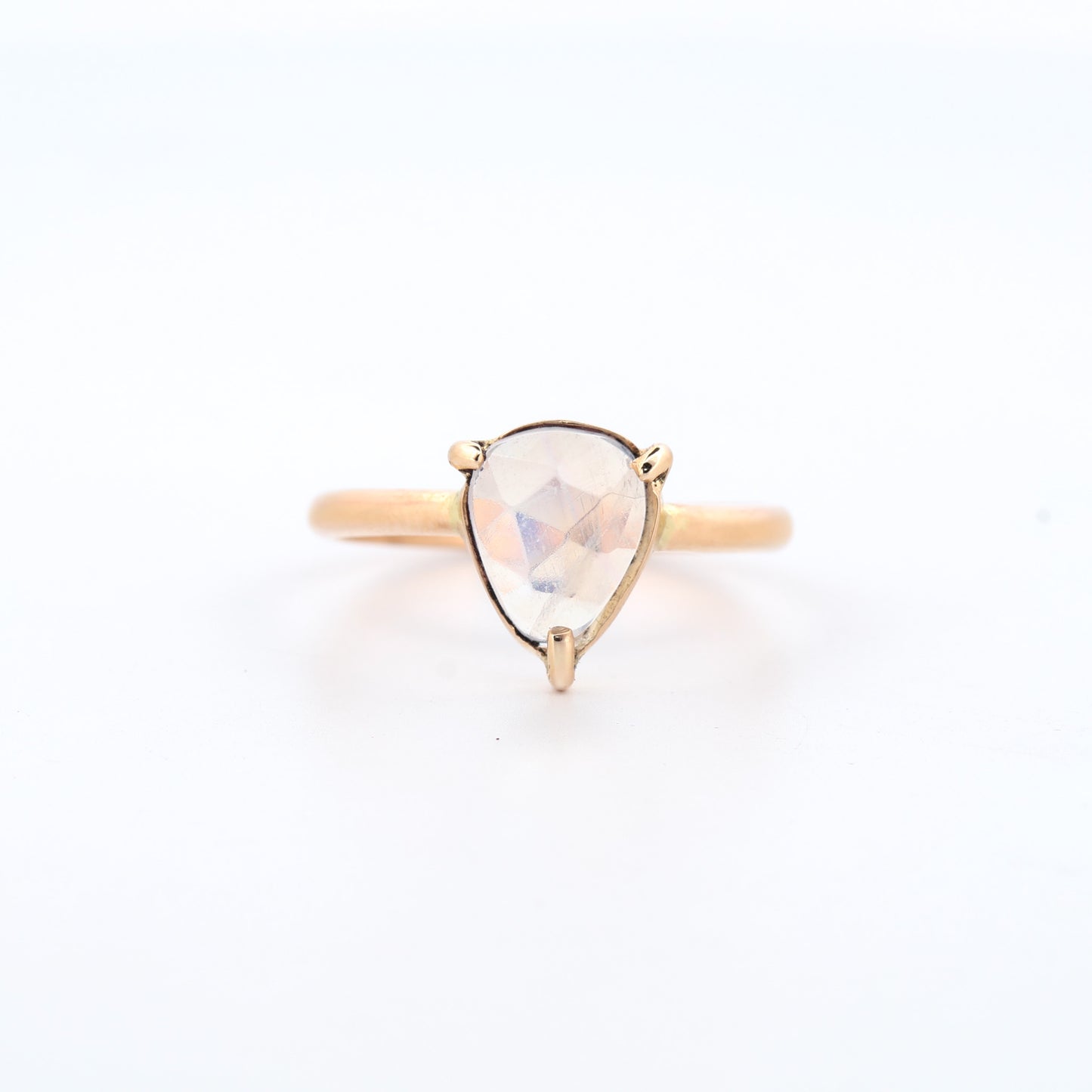 Gold ring with a teardrop-shaped gemstone on a white background