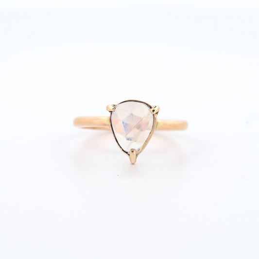 Gold ring with a teardrop-shaped gemstone on a white background